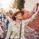 Travel, education and a teacher with students on school field trip, on urban tour. Woman, city guide and group of happy tourists, pointing at local architecture and learning on international holiday.